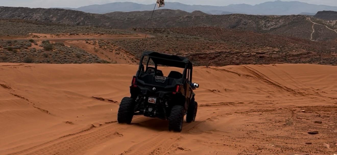 UTV on red sand dunes with rocky mountains in Hurricane, Utah